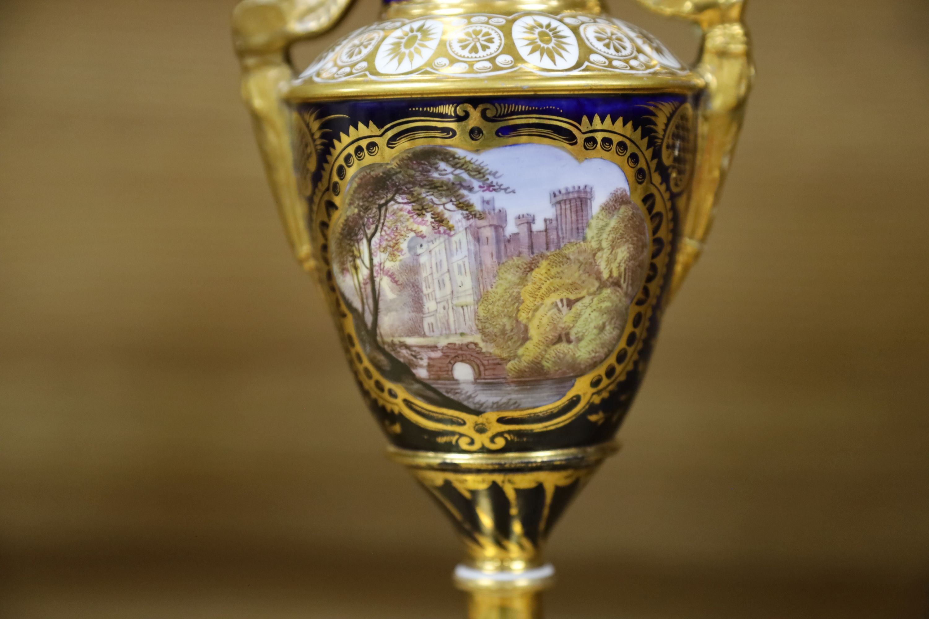 A garniture of three early 19th century English porcelain vases, c.1815-20, each painted with topographical views, tallest 26cm